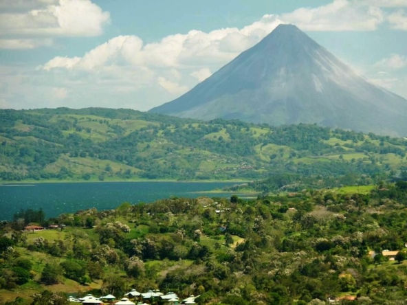 Expansive view of Lake Arenal and Arenal Volcano from Hacienda Poseidon in Guanacaste, Costa Rica, showcasing lush green hills and serene countryside.